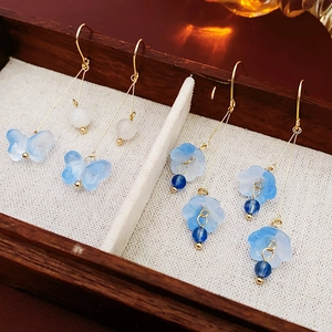 Detail of blue resin butterfly and flower earrings with golden hooks in a wooden box