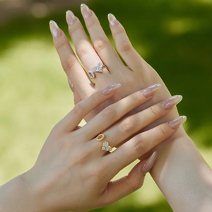 Close-up of gold and silver adjustable rings with heart zircon and letter D on grass