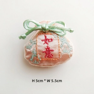 Macro detail of pink satin embroidered fortune bag accessory with Ruyi character and bow