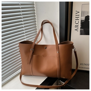 Detail of a brown large-capacity tote bag featuring a front pocket and snap button closure