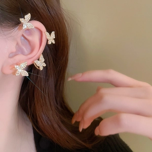 Detailed close-up of a sparkling gold butterfly ear cuff set with white rhinestones