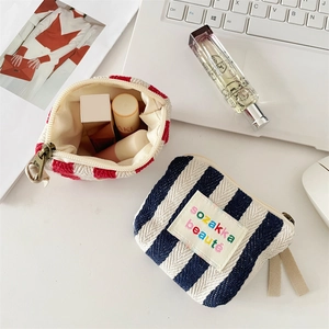 Vertical striped canvas makeup bags with brass zippers and embroidered textile labels