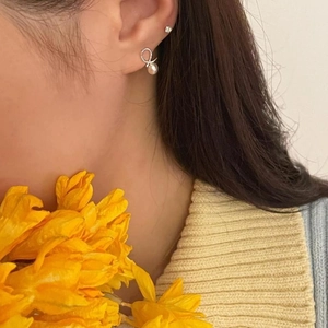 Elegant 925 sterling silver ribbon bow earrings with a white pearl on a female model