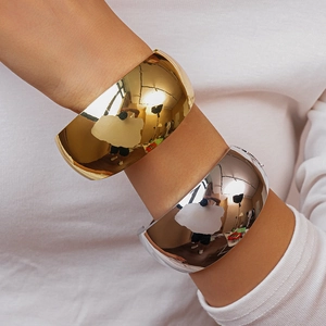 Close-up of wide irregular metal bangles in polished gold and silver finishes
