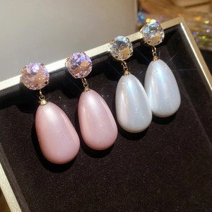 Close-up of pink and white teardrop pearl earrings with zircons on velvet box
