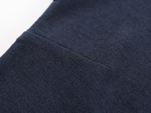 Detailed close-up of dark blue knit fabric showing texture and reinforced stitching