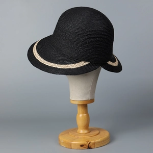 Detail of elegant black woven cloche hat with beige decorative brim and fine straw texture