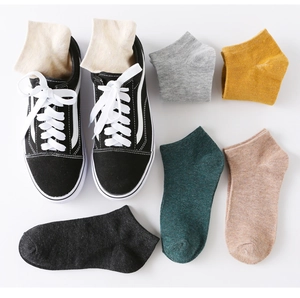 Flat lay of colorful low-cut cotton socks for men and women next to black casual sneakers