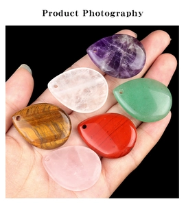 Macro view of six teardrop natural crystal pendants held in hand with pre-drilled holes