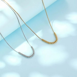 Minimalist gold and silver beaded snake bone necklaces on a light blue background