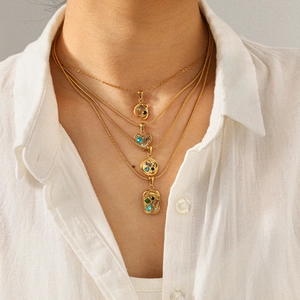 Détail de colliers multicouches en or 18 carats avec pendentifs pierres colorées sur mannequin