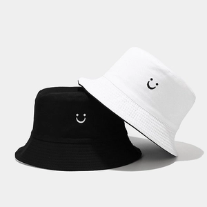 Close-up of black and white cotton bucket hats featuring minimalist smiley face embroidery