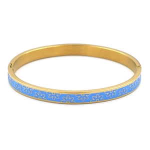 Detail view of gold-tone stainless steel bangle with blue enamel daisy floral pattern