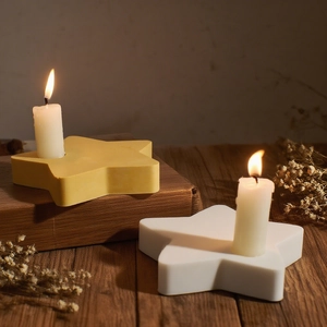 Star-shaped resin candle holder set in white and yellow on a rustic wooden table