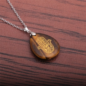 Detail of Hamsa Hand engraved on brown gemstone pendant with a silver stainless steel chain
