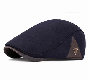 Detail of navy blue newsboy cap featuring side leather patch and metal fashion emblem