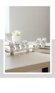 Detalle de seis figuras de gato de resina blanca con cascabeles dorados en escritorio