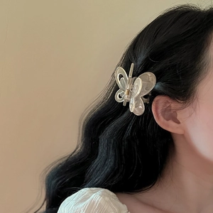 Detailed view of an elegant hollow butterfly hair claw in creamy white acrylic on hair