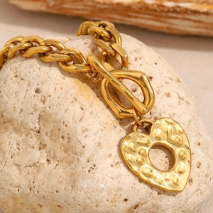 Détail du bracelet chaîne gourmette plaqué or 18K avec pendentif cœur martelé et fermoir OT