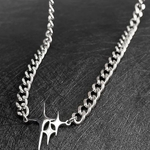 Detailed macro view of a silver Cuban chain necklace with a cross star pendant