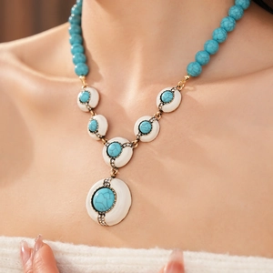 Close-up of vintage resin necklace with turquoise beads and white round pendant on a model