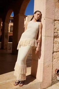 Dettaglio di set gilet in maglia e gonna lunga bianco crema con nappe a frangia bohémien