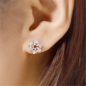 Detailed macro view of a floral silver stud earring with sparkling crystals on a model