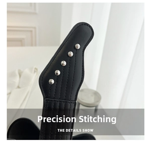 Detail of precise stitching and silver rivets on the black leather guitar bag strap