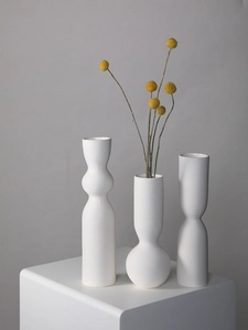 Detailed macro view of matte white ceramic vases with refined horizontal ribbed textures