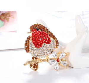 Detailed macro view of a vintage bird brooch with red rhinestones on a gold branch