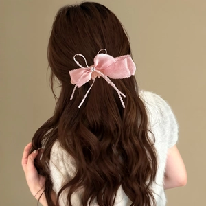 Détail d'une élégante pince à cheveux en dentelle rose sur de longs cheveux bruns ondulés
