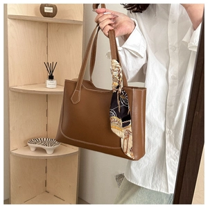 Gros plan du sac cabas en cuir marron avec foulard décoratif en soie en ambiance