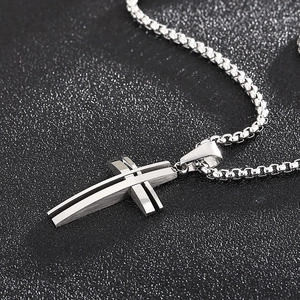 Close-up of a silver hollow-out layered cross pendant with a matching box chain