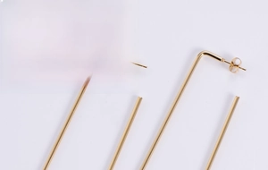 Macro detail of large gold-plated square hoop earrings with a minimalist wire design