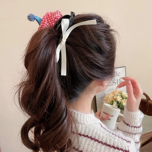 Detail of cute cat bow hair clip with red plaid and blue pompom on low ponytail