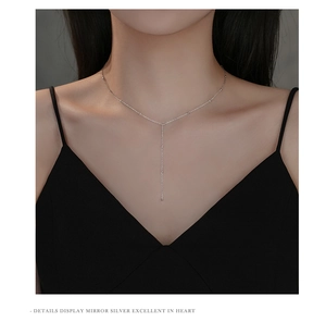 Detail view of a dainty S925 sterling silver Y-shaped tassel necklace on a model
