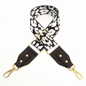 Detail of leopard print wide strap with black leather ends and gold metal hardware hooks