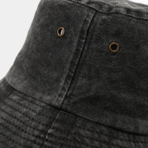 Detail of washed cotton bucket hat showing dark denim texture and metal eyelets