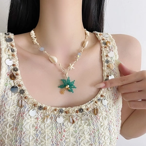 Primo piano della collana boho con conchiglie e ciondolo a forma di palma