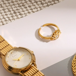 Detailed close-up of a gold-tone sunburst ring with sparkling cubic zirconia on white background