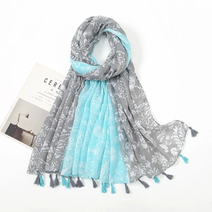 Detail of soft voile shawl with blue floral print and fringe tassels on white background