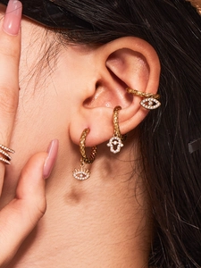 Detailed shot of 18k gold evil eye and hamsa hand earrings with white cubic zirconia