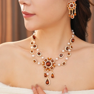 Nahaufnahme der Vintage Goldkette und Perlenohrringe mit Bernstein am Model