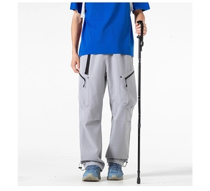Close-up of light grey cargo pants featuring multiple zipper pockets and adjustable cuffs