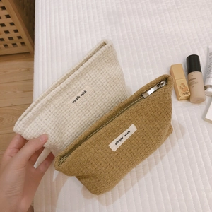 Textured woven canvas makeup pouches in cream and yellow with zipper closure