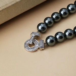 Macro shot of dark grey pearl necklace with a silver pavé zircon circular clasp