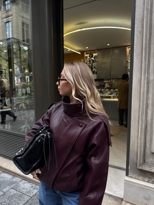 Détail de veste en cuir bordeaux surdimensionnée avec col montant et fermeture éclair