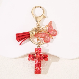 Custom resin cross keychain with red stones, pink butterfly, and tassel on gold ring