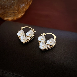Elegant gold-plated heart earrings with zircon flowers and pearls on a black leather base