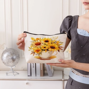 Linen sunflower and teacup makeup bag with top zipper closure held by a model